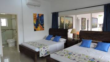 A hotel room with two wooden beds, a bathroom, and a view of the outdoors.