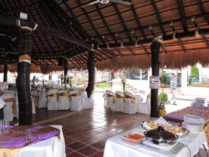 Formal gatherings take place in this elegant space with round tables, white tablecloths, and golden accents.