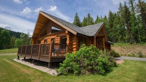 A log cabin with a deck, surrounded by a forest and a clear sky. - Alpine Meadows Resort (Clearwater)
