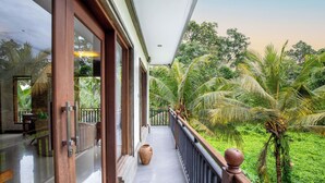 A balcony with a view of lush greenery and palm trees. - Amoya Inn (Ubud)