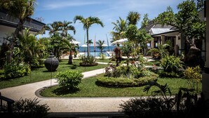 Une cour d’hôtel avec une piscine, des palmiers et une vue sur l’océan.