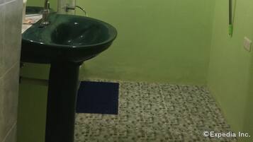 Ein Badezimmer mit grüner Wand, einem Waschbecken, einem Spiegel und einer Dusche mit Glastür und Duschkopf.