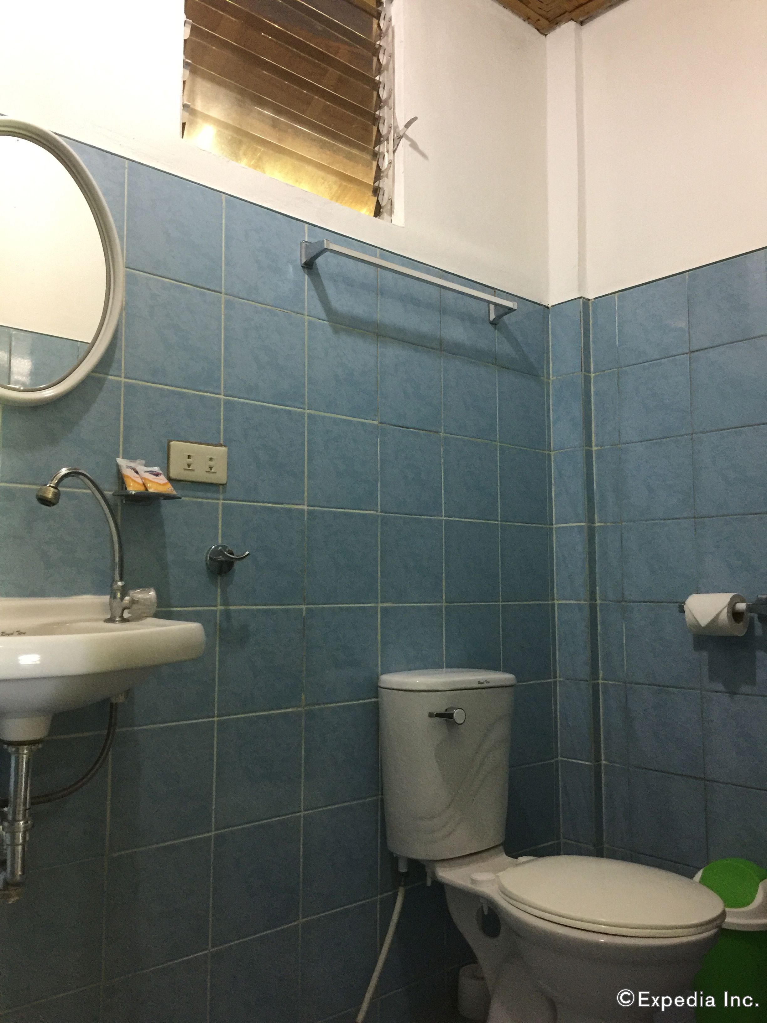 A bathroom with blue tiles, a white sink, a toilet, and a mirror.