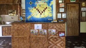 A reception desk with a map of the Maldives, a mirror, and various informational signs. - Bohol Lahoy Dive Resort (Guindulman)