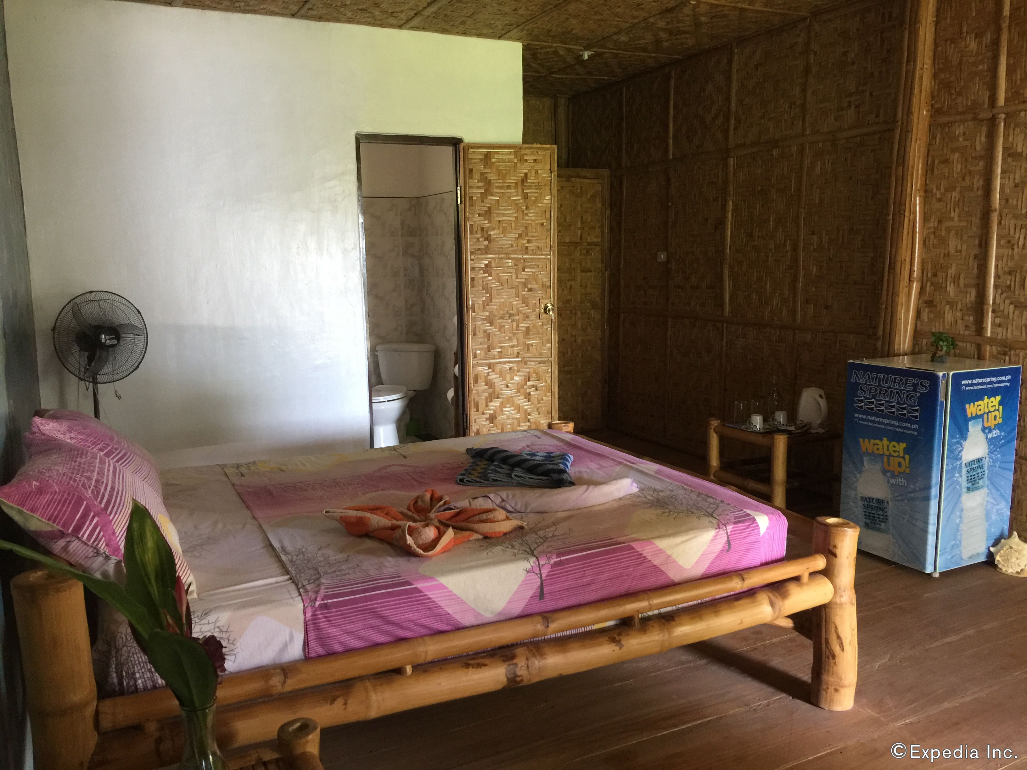 Una habitación con cama, ventilador, inodoro y dispensador de agua.
