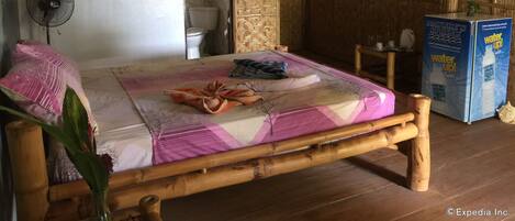 Una habitación con cama, ventilador, inodoro y dispensador de agua.
