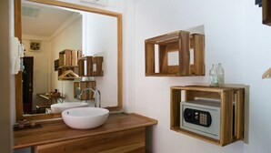 A bathroom with a wooden vanity, a large mirror, and a built-in radio. - Cold River (Luang Prabang)