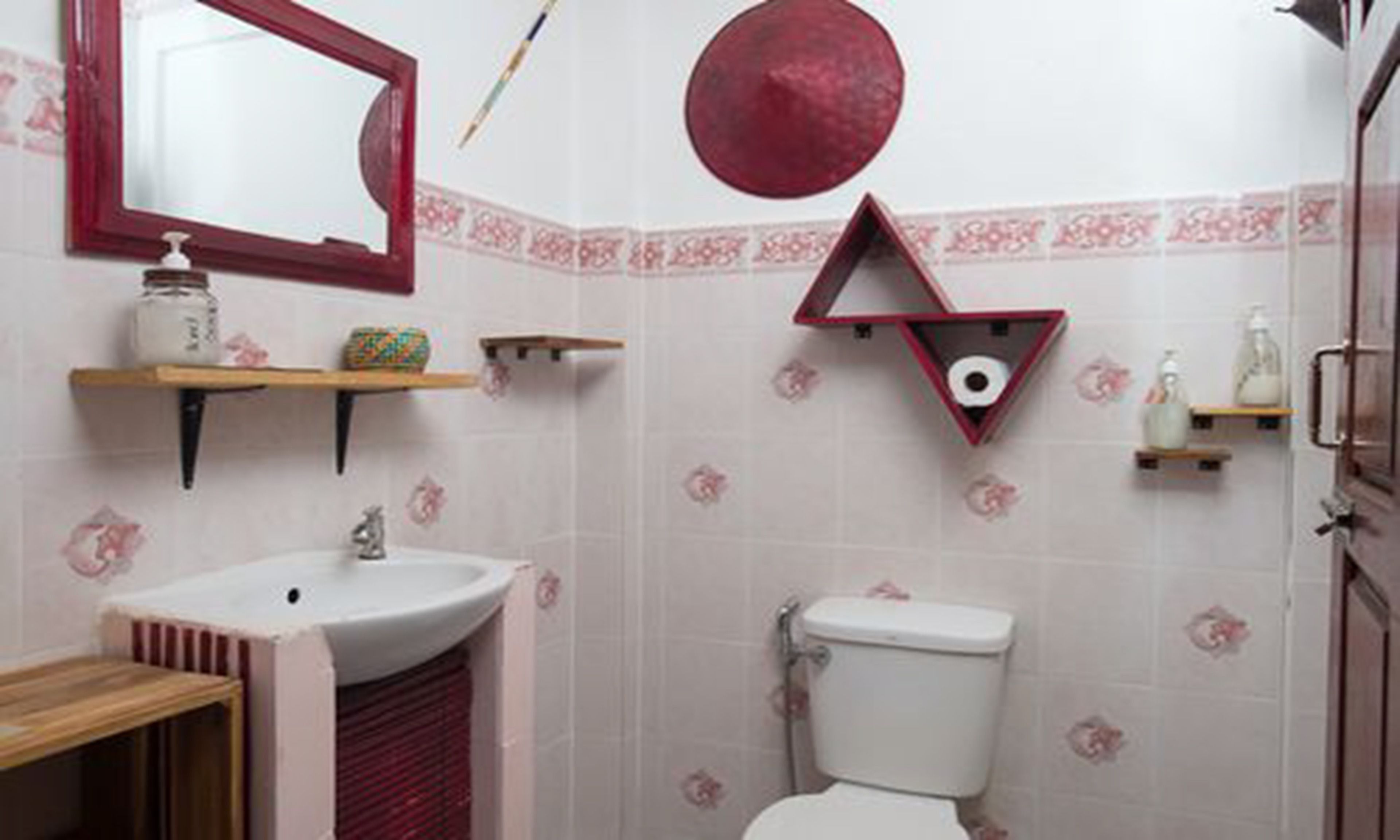 Ein Badezimmer mit Waschbecken, Spiegel, Toilette und dekorativen Wandfliesen.