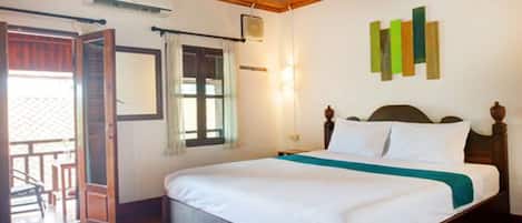 A bedroom with a wooden ceiling, a bed with white bedding, a green accent, a window with curtains, and a wall-mounted air conditioning unit.