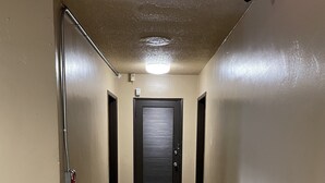 A corridor with a tiled floor, a black door at the end, and a fire alarm on the left wall. - Valley Motel El Cajon-San Diego (El Cajon)