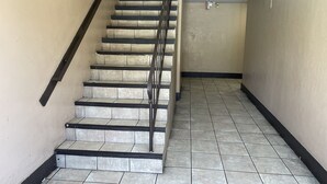 A staircase with black railings and beige walls, leading to an upper floor. - Valley Motel El Cajon-San Diego (El Cajon)