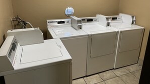 A laundry area with four washers and dryers, a water heater, and a window. - Valley Motel El Cajon-San Diego (El Cajon)