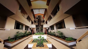 A modern hotel atrium with a central garden, multiple floors, and a symmetrical design. - Panchalae Boutique Residences (Pattaya)