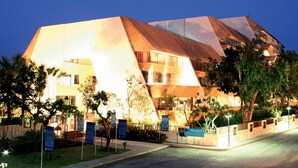 A modern hotel with a unique geometric facade, multiple balconies, and a well-lit entrance area. - Panchalae Boutique Residences (Pattaya)