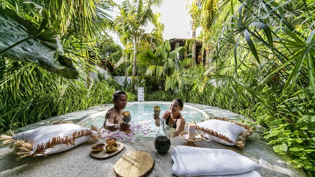 Two people sitting by a pool surrounded by lush greenery. - Buena Vida Resort and Spa (Daanbantayan)