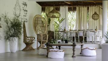 A dining area with a wooden table, white chairs, and hanging wicker lamps.