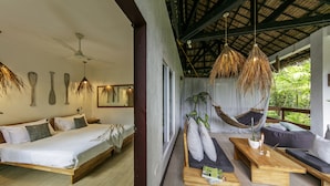 A bedroom with a bed, bedside tables, and a hanging chair. - Buena Vida Resort and Spa (Daanbantayan)