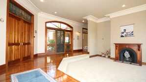 A spacious living room with hardwood floors, a large white carpet, a fireplace, and a wooden door with glass panels. - Relaxin (Middle Dural)