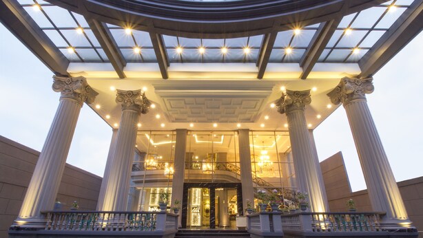 A grand entrance with large columns, a glass ceiling, and a staircase leading to the upper floor. - Park View Hotel (Bandung)