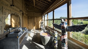 A wooden interior with a large window, a stone bathtub, and totem poles.
