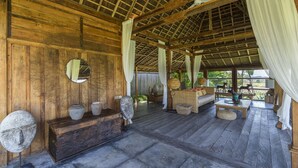 A rustic wooden room with a high ceiling, a wooden bench, a small table, and a sofa.