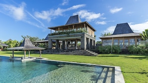 A large house with a swimming pool, a covered patio, and a well-maintained lawn.