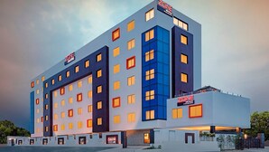 Un hotel de varios pisos con un diseño moderno, destacando un cartel grande que dice 'ZONE' en la parte superior.