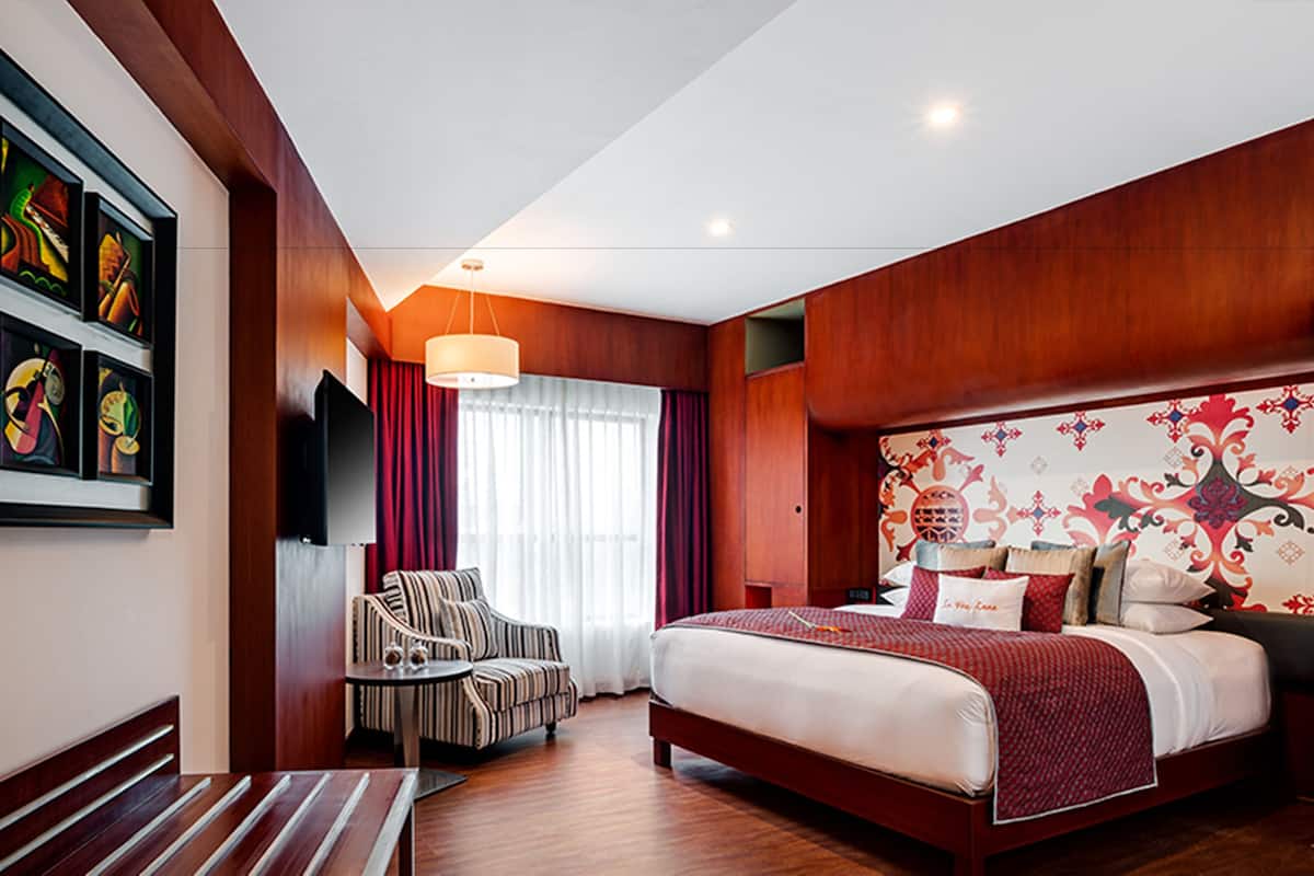 A hotel room with a large bed, a TV mounted on the wall, a chair, and a table.