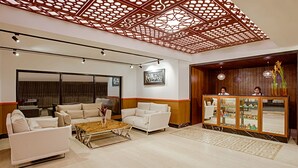 Un vestíbulo moderno con mostrador de recepción, zona de estar y techo decorativo.