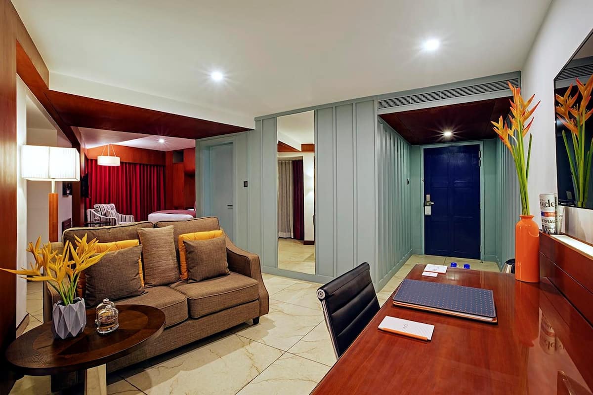 A modern hotel room with a living area, a dining table, and a separate bedroom.