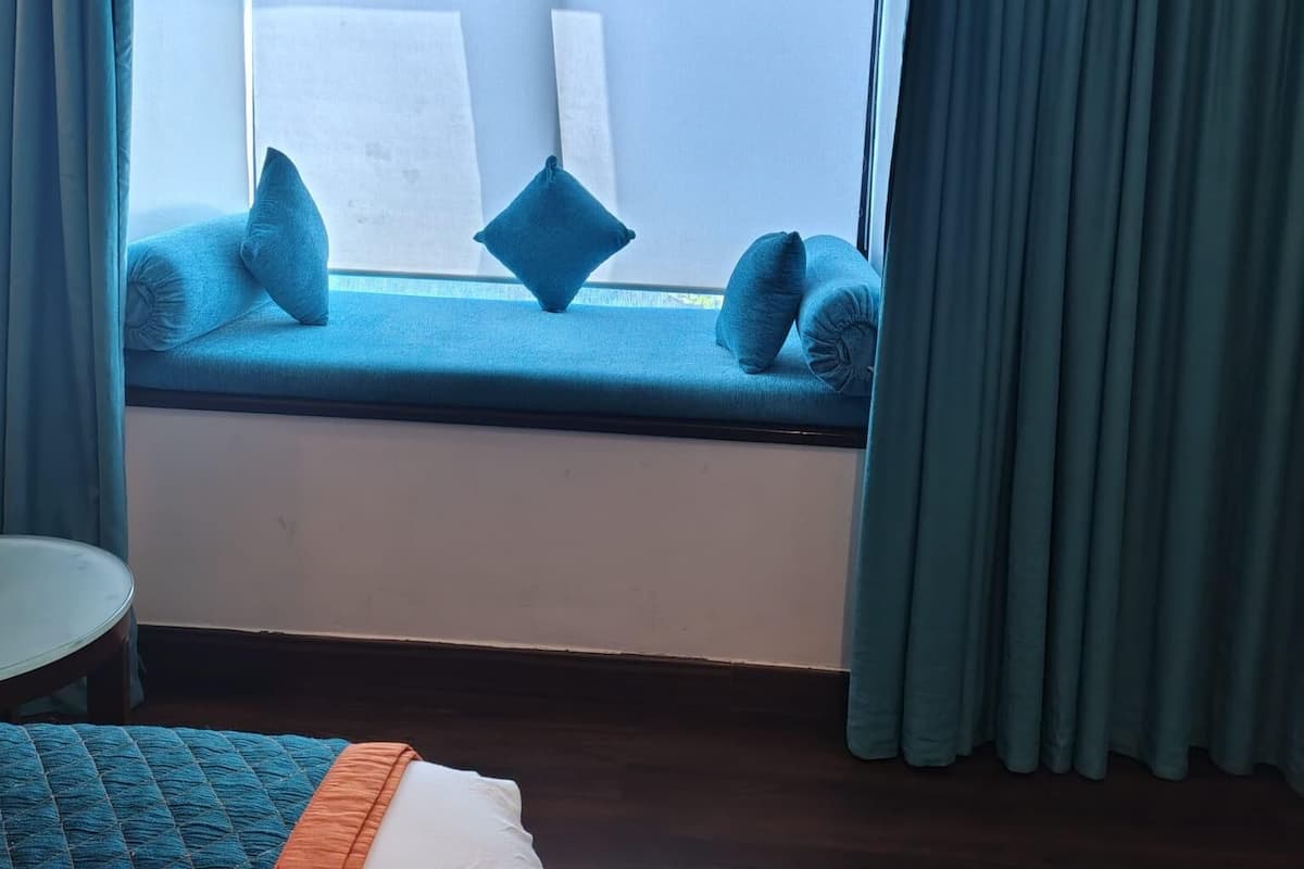 A room with a window seat, blue cushions, and a view of the sky.