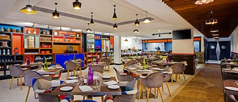 Un restaurante espacioso con varias zonas de comedor, techos altos y luminarias modernas.