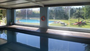 A swimming pool with a view of a backyard with a slide and lounge chairs. - Quinta Vale do Homem (Amares)