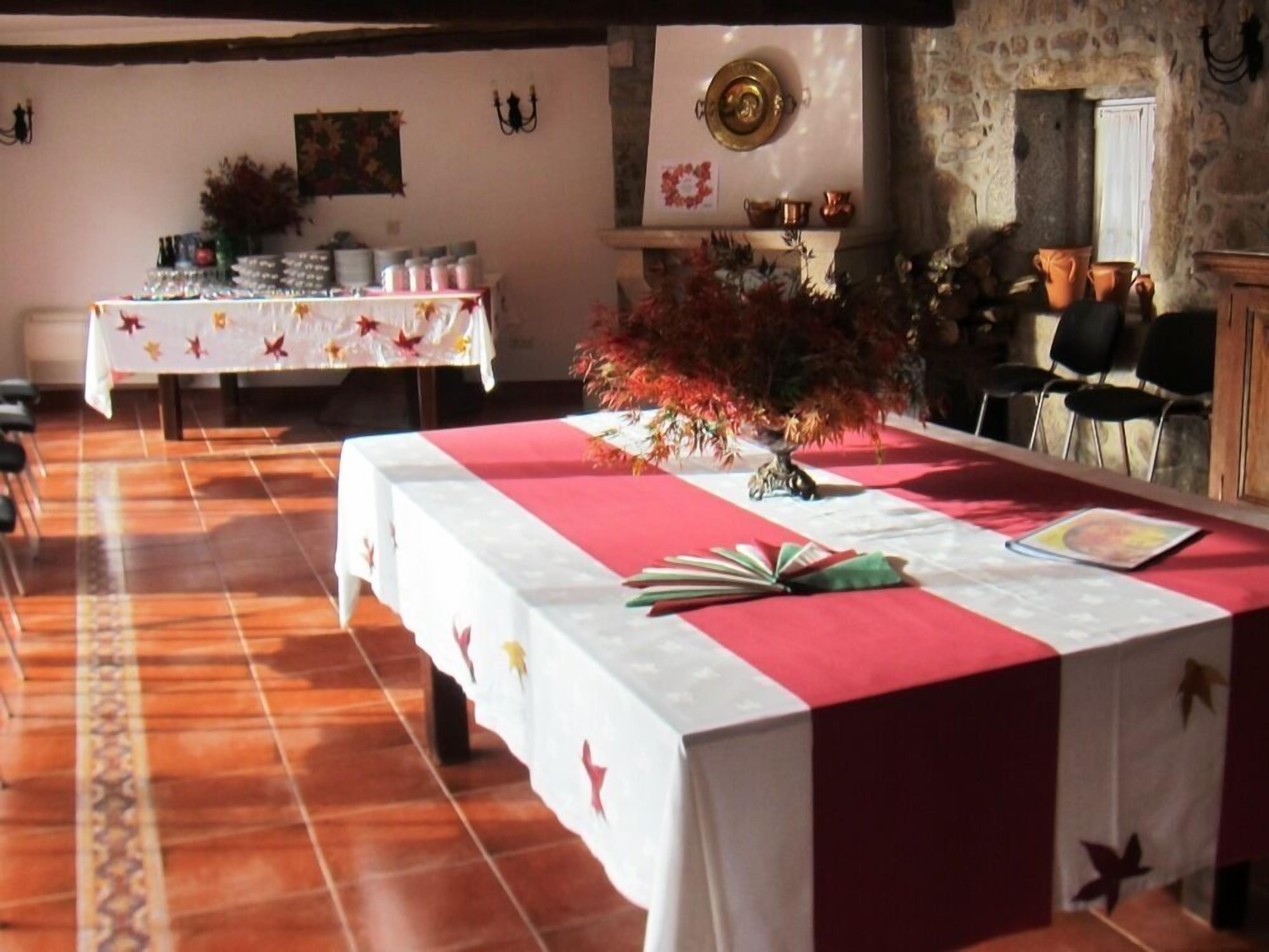 A dining area with a long table covered in a red and white tablecloth, surrounded by chairs.