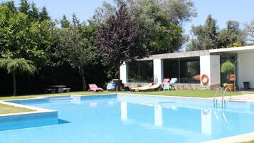 Relax by the pool surrounded by lush greenery and comfortable lounge chairs.