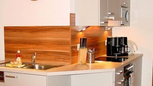 A compact kitchen with a wooden backsplash, a coffee maker, and a sink.