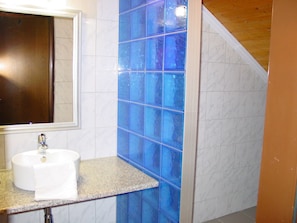 A bathroom with a sink, mirror, and blue-tiled wall.