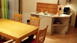A compact kitchen with a wooden table and chairs, a sink, and a clock on the wall.