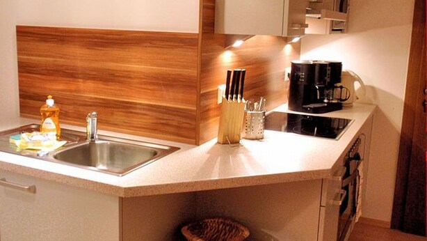 A modern kitchen with a wooden backsplash, a sink, a coffee maker, and a knife holder.