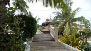 A staircase leading to a building with a satellite dish, surrounded by tropical vegetation. - Bearland Paradise Resort (Tigbauan)