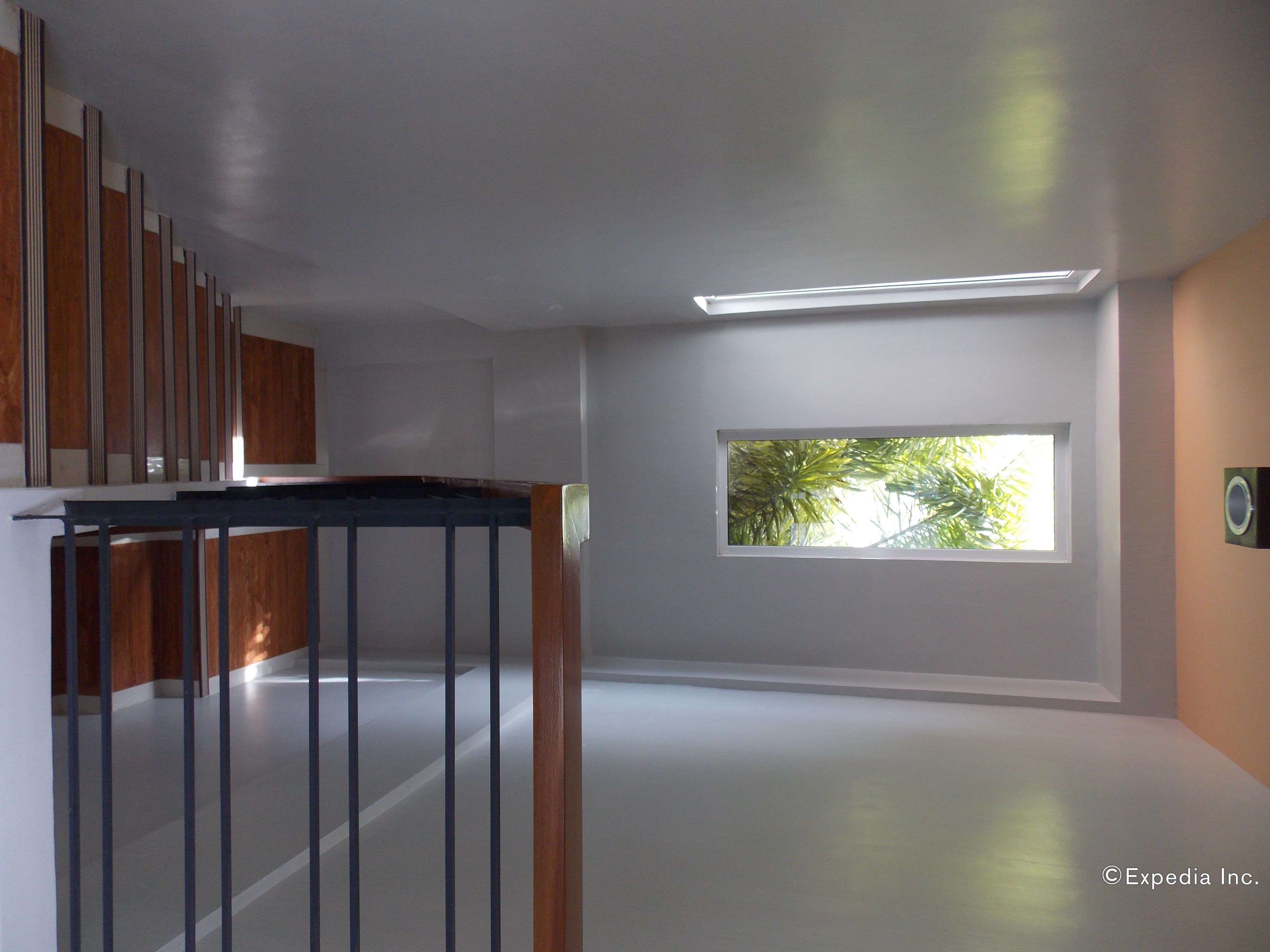 A modern interior with a staircase, a large window with a view of trees, and a ceiling light fixture.