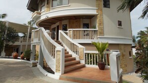 A two-story house with a curved balcony, a staircase with white railings, and potted plants. - Bearland Paradise Resort (Tigbauan)