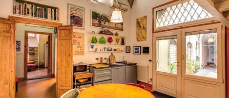 A cozy kitchen with wooden furniture, a dining table, and a view of the garden through the window.