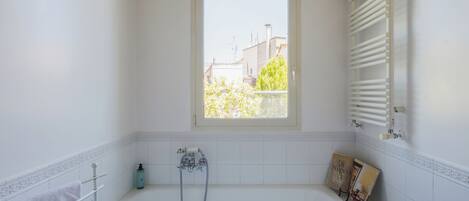 A bathroom with a bathtub, a window, and a towel rack.