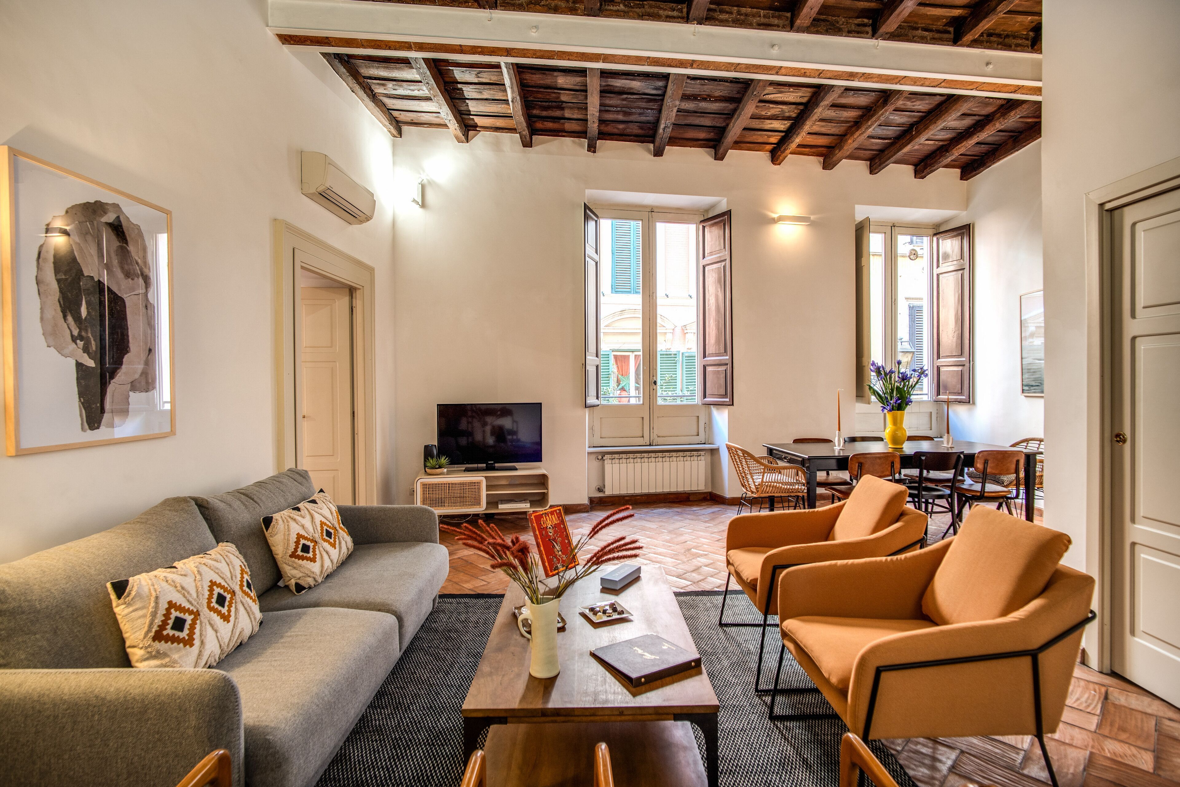 A living room with a sofa, armchairs, a coffee table, and a TV.