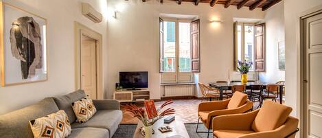 A living room with a sofa, armchairs, a coffee table, and a TV.
