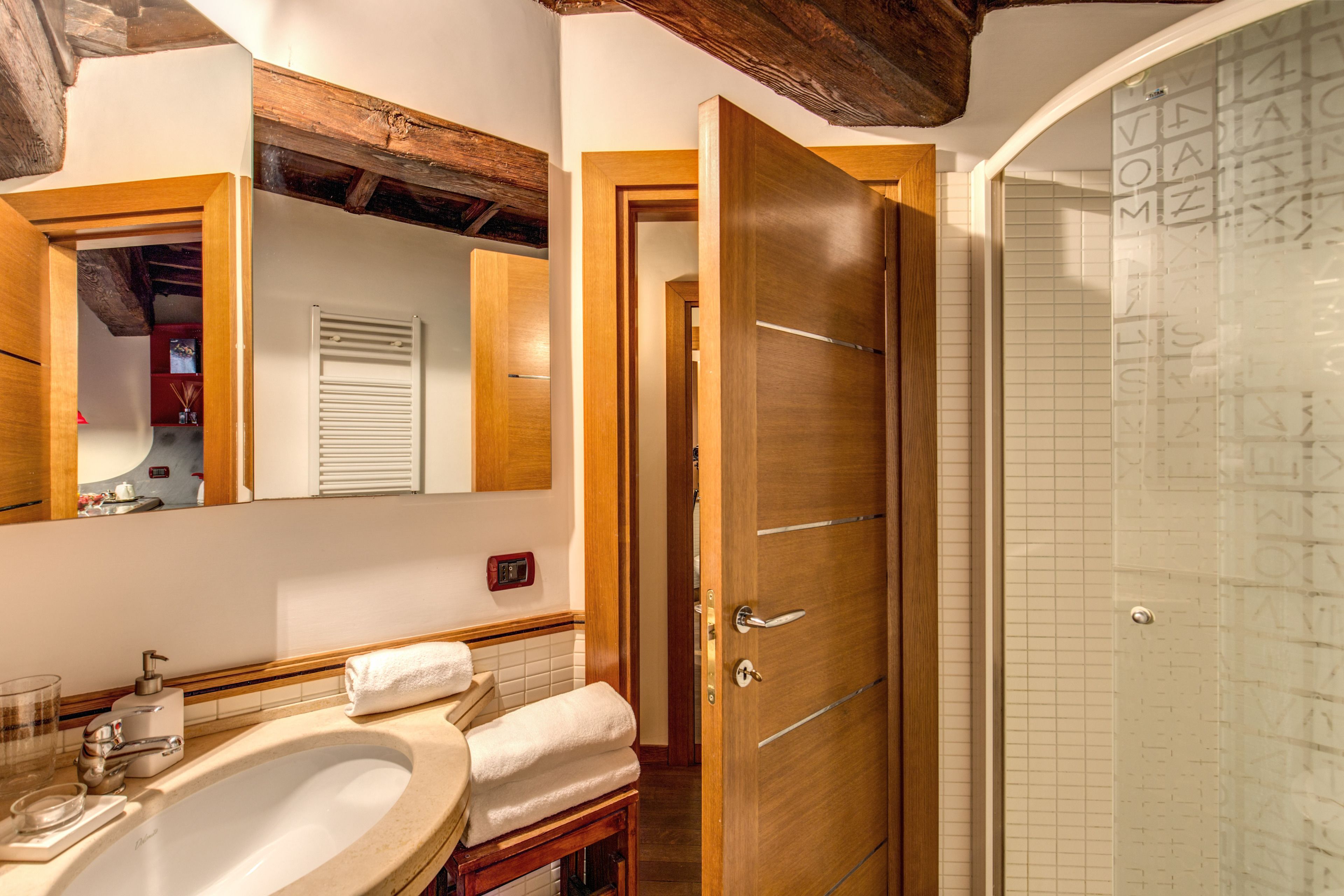 A bathroom with a wooden door, a sink, and a mirror.