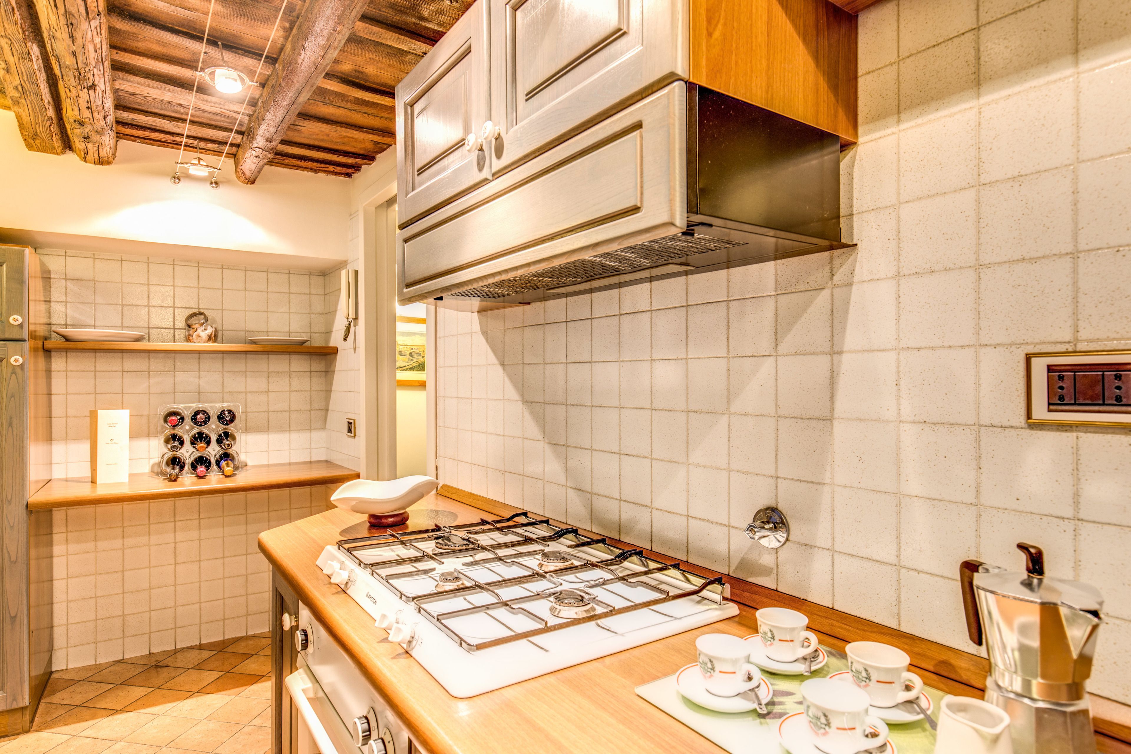 A kitchen with a gas stove, wooden cabinets, and a tiled backsplash.