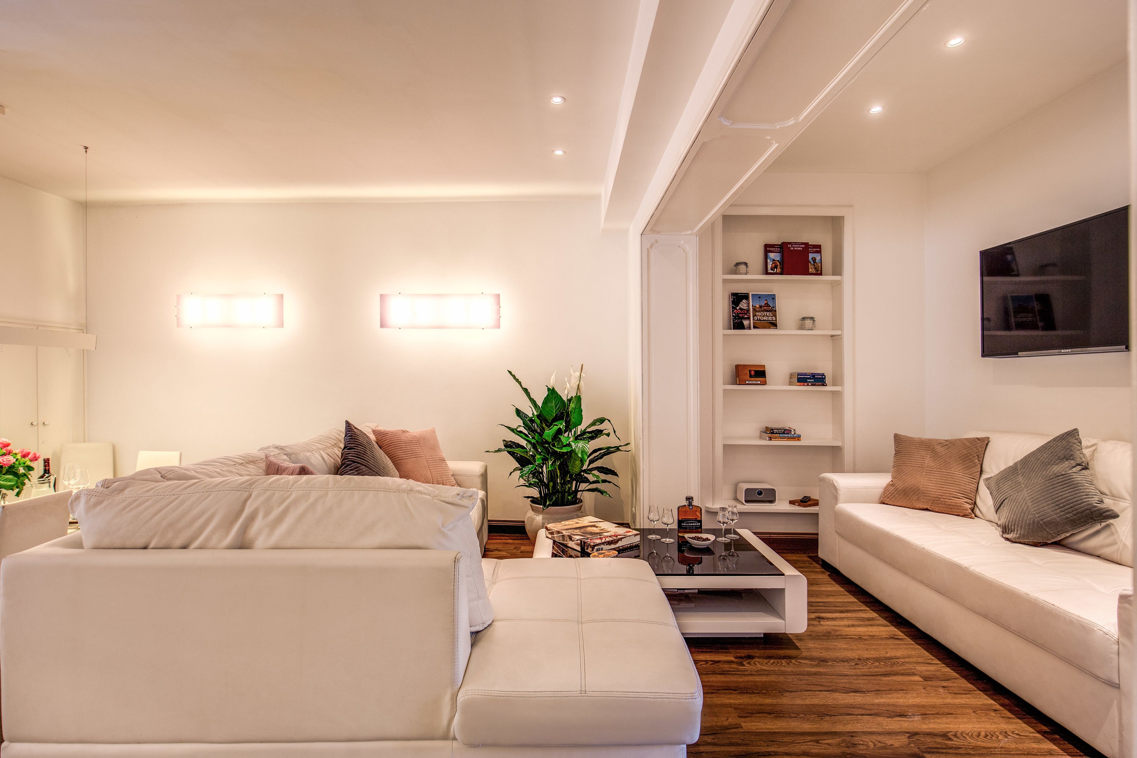 A modern living room with a white sofa, a coffee table, and a bookshelf.