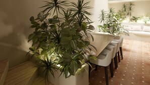 A spacious dining area with a high arched brick ceiling, a long table with chairs, and several potted plants. - Your Suite Rome (Rome)
